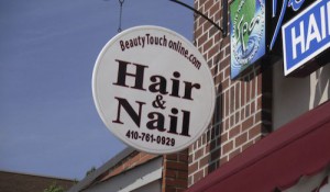A sign that says hair & nail on the side of a building.