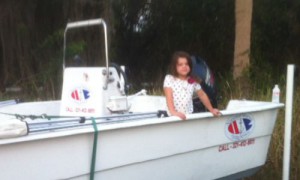 A little girl sitting on the back of a white boat.