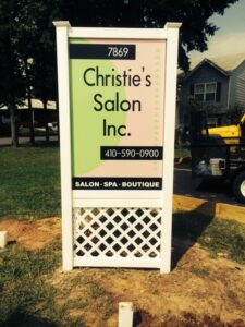 A vertical roadside sign for christie's salon inc., displaying the salon's name, phone number, and the services offered: salon, spa, boutique.