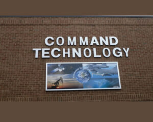 Exterior wall of a building with a sign reading 'command technology' in large white letters and a digital billboard featuring technological imagery below.